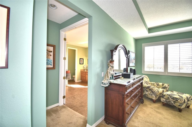 hallway featuring light colored carpet and a textured ceiling