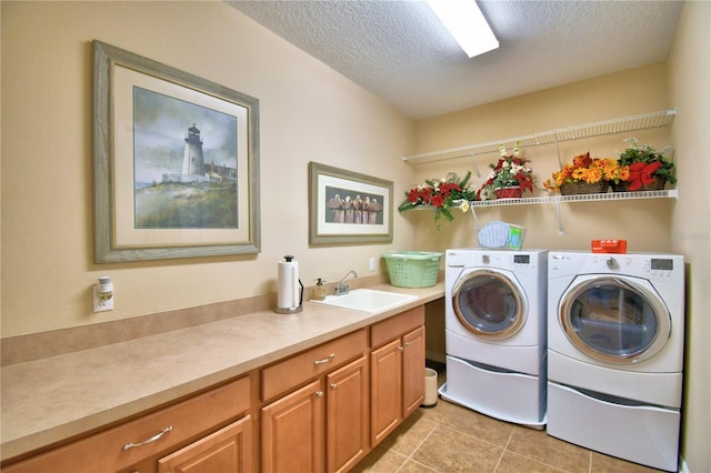 clothes washing area featuring light tile patterned floors, sink, washing machine and dryer, and a textured ceiling