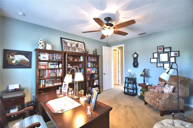 carpeted home office featuring a textured ceiling and ceiling fan