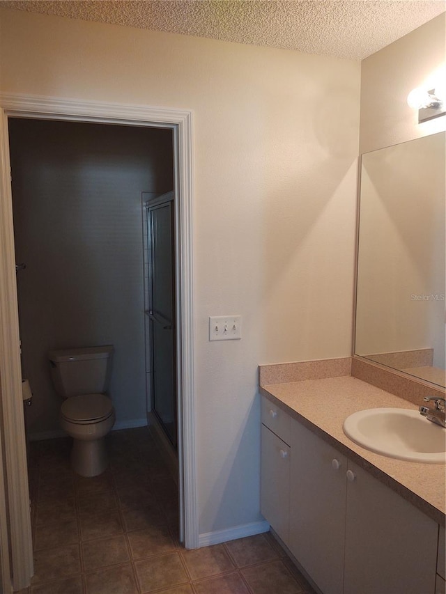 bathroom featuring tile patterned flooring, vanity, toilet, a shower with door, and a textured ceiling