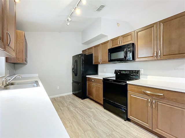 kitchen featuring sink, vaulted ceiling, black appliances, and rail lighting