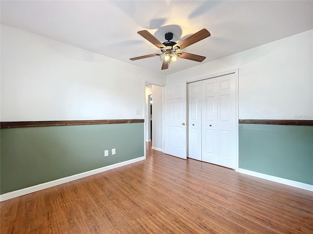 unfurnished bedroom featuring ceiling fan, wood-type flooring, and a closet