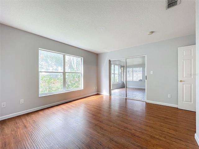 empty room with hardwood / wood-style floors and a textured ceiling