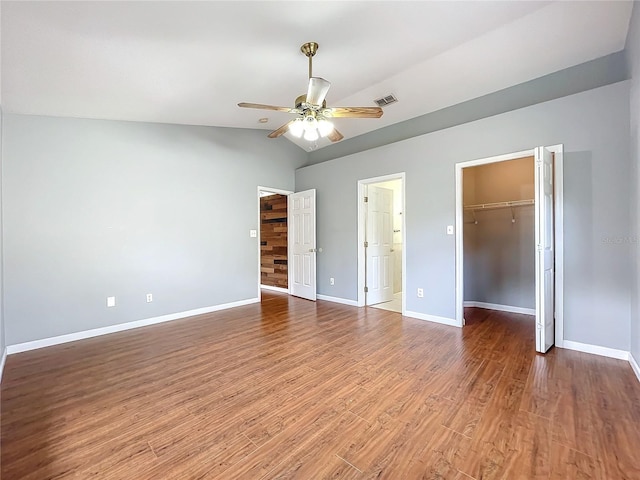 unfurnished bedroom with a walk in closet, hardwood / wood-style flooring, vaulted ceiling, and a closet