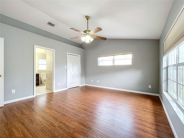 unfurnished bedroom featuring lofted ceiling, ensuite bath, a closet, hardwood / wood-style flooring, and ceiling fan