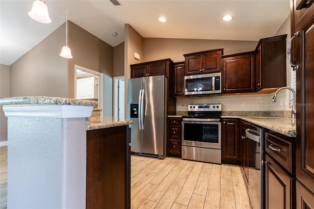 kitchen featuring a sink, vaulted ceiling, backsplash, dark brown cabinets, and appliances with stainless steel finishes
