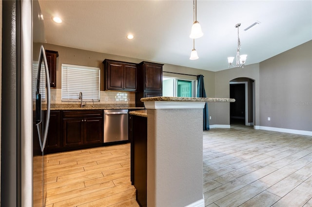 kitchen with light wood-type flooring, stainless steel appliances, dark brown cabinets, and arched walkways