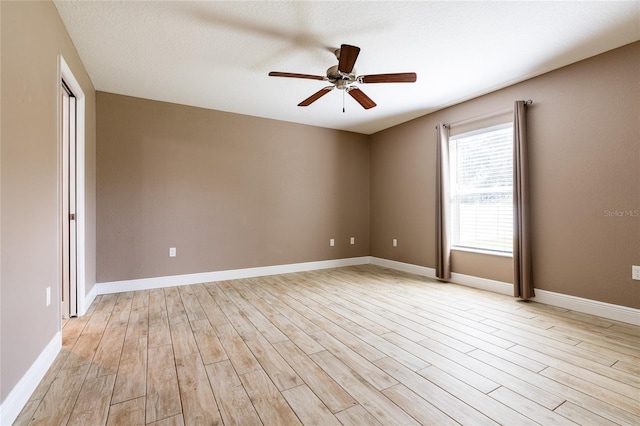 empty room with light wood finished floors, baseboards, and a ceiling fan