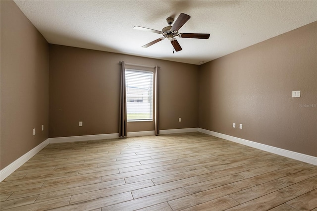 empty room with ceiling fan, a textured ceiling, baseboards, and light wood-style flooring