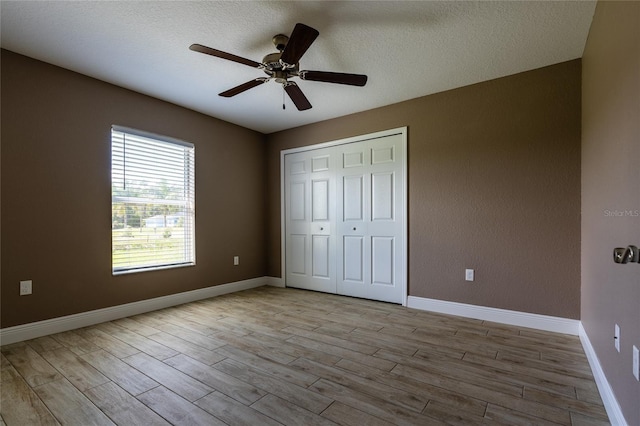 unfurnished bedroom with a textured ceiling, a closet, a ceiling fan, and wood finished floors