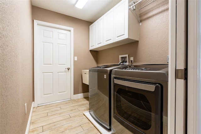 laundry room with baseboards, wood finish floors, separate washer and dryer, cabinet space, and a textured wall
