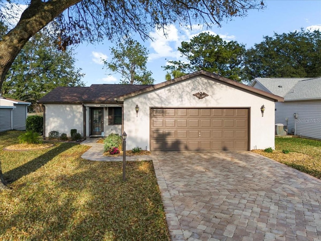 ranch-style home featuring a garage, a front yard, and central air condition unit