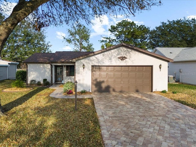 ranch-style home featuring a garage, a front yard, and central air condition unit