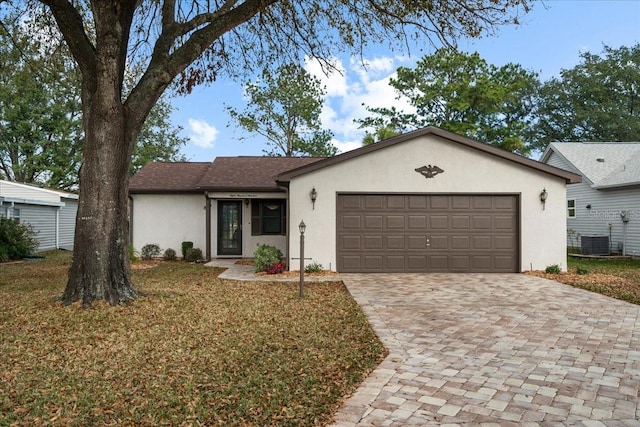 ranch-style home featuring a garage, central AC unit, and a front lawn