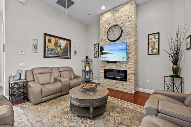 living room with a high ceiling, wood-type flooring, and a fireplace