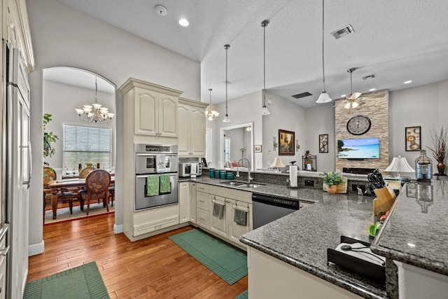 kitchen with sink, hanging light fixtures, kitchen peninsula, stainless steel appliances, and cream cabinets