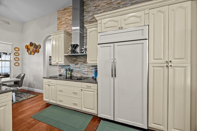 kitchen featuring cream cabinets, dark hardwood / wood-style floors, backsplash, and wall chimney exhaust hood