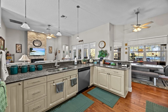 kitchen featuring sink, dark stone countertops, hanging light fixtures, stainless steel dishwasher, and cream cabinets