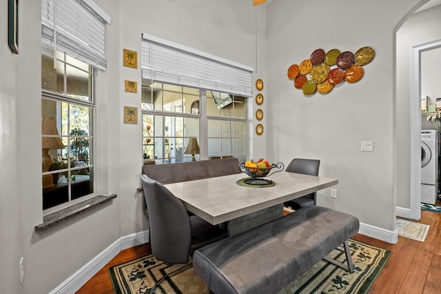 dining room featuring wood-type flooring, washer / dryer, and a high ceiling