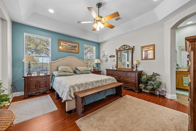 bedroom featuring a raised ceiling, ceiling fan, and dark hardwood / wood-style flooring