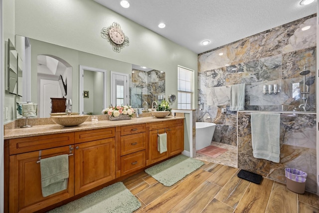 bathroom featuring plus walk in shower, vanity, and a textured ceiling