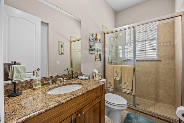 bathroom featuring vanity, a shower with door, and toilet