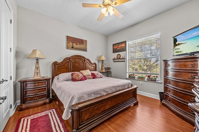 bedroom with ceiling fan, wood-type flooring, and a textured ceiling