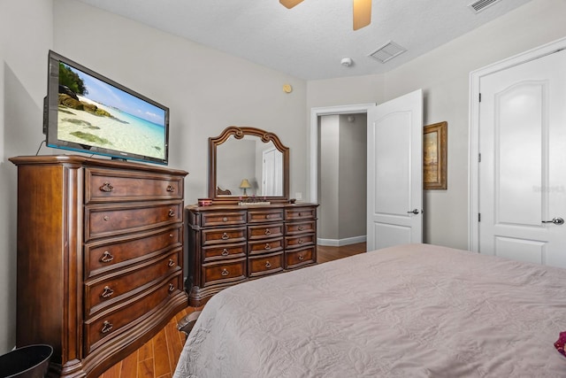 bedroom featuring ceiling fan, hardwood / wood-style floors, and a textured ceiling