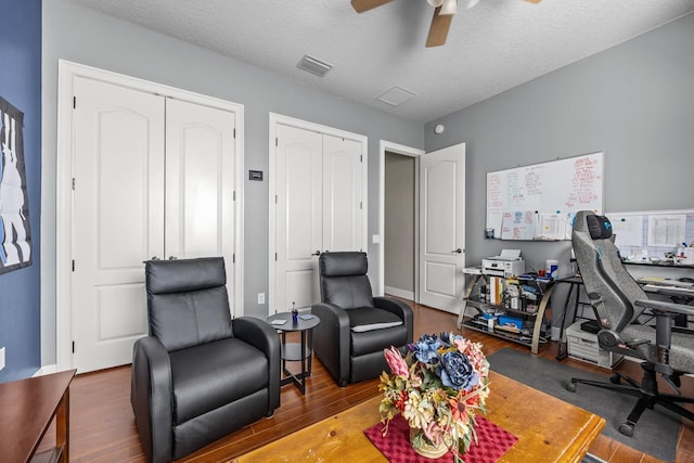 home office with dark hardwood / wood-style floors, a textured ceiling, and ceiling fan