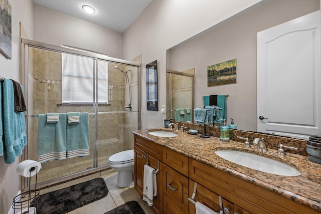 bathroom with tile patterned flooring, vanity, a textured ceiling, toilet, and walk in shower