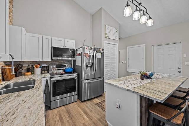 kitchen with a kitchen bar, white cabinetry, a center island, appliances with stainless steel finishes, and pendant lighting