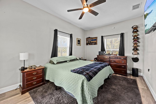 bedroom with multiple windows, light hardwood / wood-style flooring, and ceiling fan