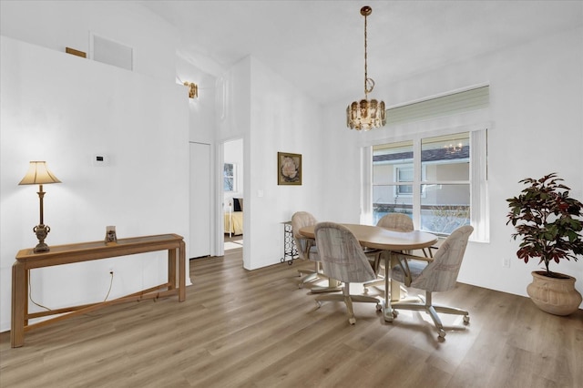 dining room featuring hardwood / wood-style flooring, a towering ceiling, and a chandelier