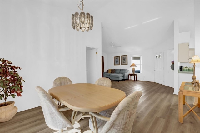 dining room with ceiling fan with notable chandelier, a towering ceiling, and hardwood / wood-style floors