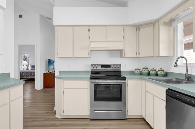 kitchen with range hood, sink, light hardwood / wood-style floors, stainless steel appliances, and cream cabinetry