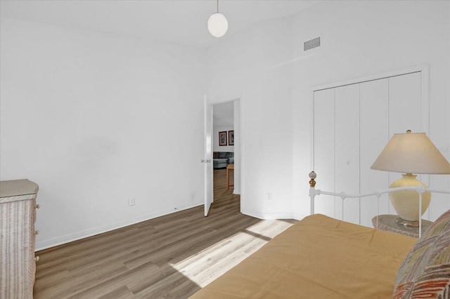 unfurnished bedroom with wood-type flooring, high vaulted ceiling, and a closet