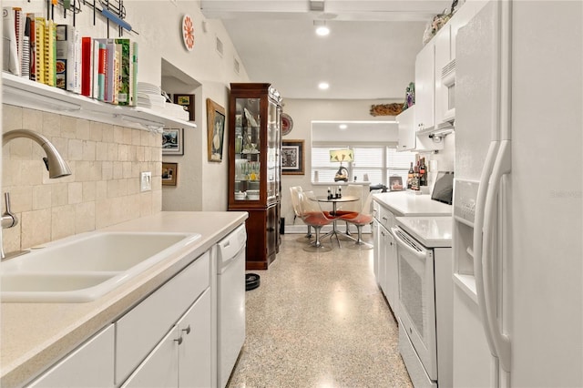 kitchen featuring light countertops, white cabinets, white appliances, light speckled floor, and a sink