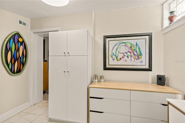 interior space featuring light tile patterned floors, baseboards, and visible vents