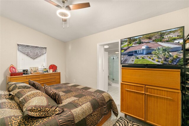 bedroom with light tile patterned floors, ensuite bath, ceiling fan, and vaulted ceiling