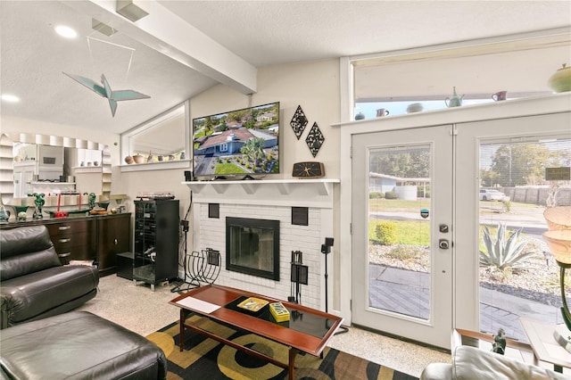 living room featuring lofted ceiling with beams, a fireplace, french doors, and a textured ceiling