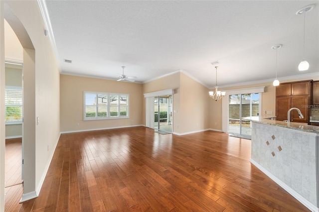 unfurnished living room with crown molding, a healthy amount of sunlight, and dark hardwood / wood-style floors