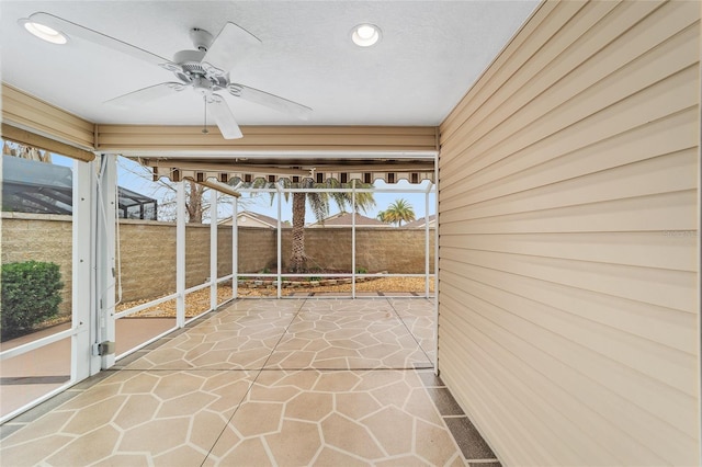 unfurnished sunroom with ceiling fan