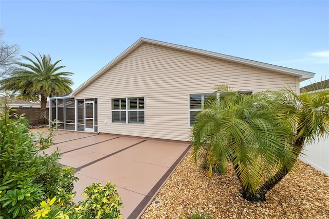 back of house with glass enclosure and a patio area