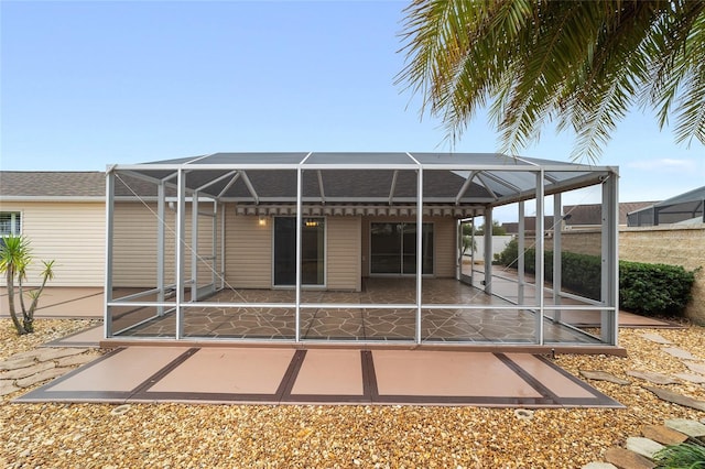 back of property with a patio and glass enclosure