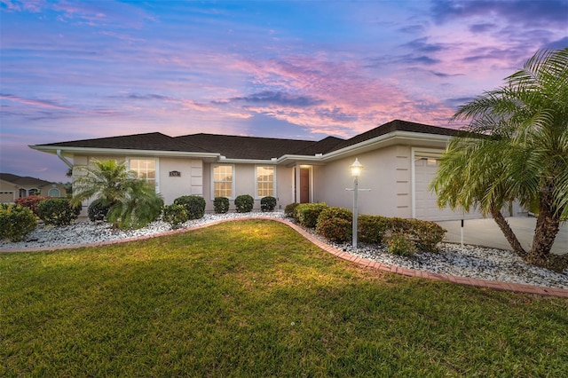 single story home featuring a garage and a lawn