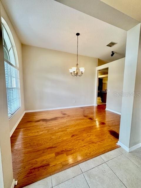 spare room with a notable chandelier and light hardwood / wood-style floors