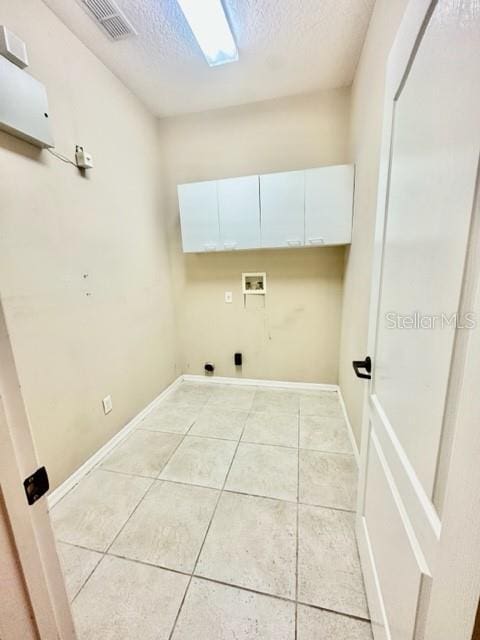 washroom featuring cabinets, washer hookup, a textured ceiling, and light tile patterned floors