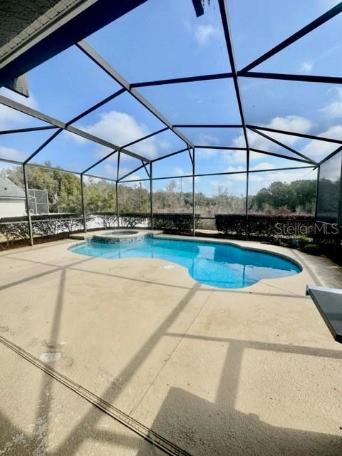 view of pool featuring an in ground hot tub, a lanai, and a patio