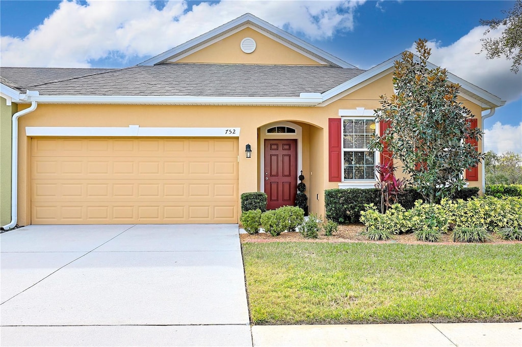 ranch-style home with a garage and a front lawn