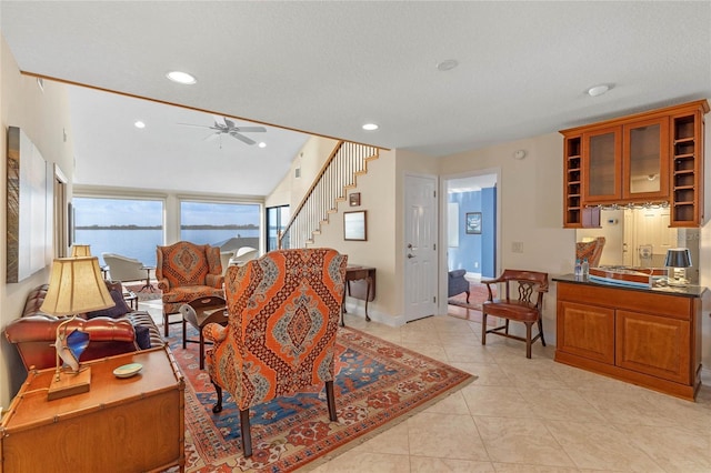 living room with a water view, light tile patterned floors, and ceiling fan